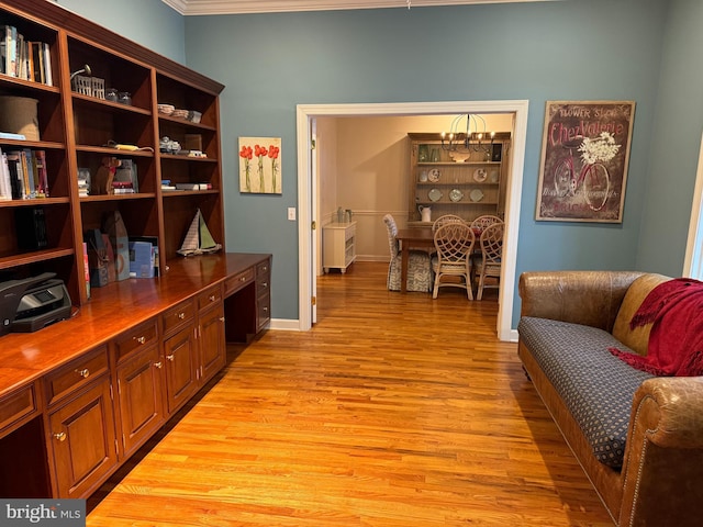 office space with built in desk, crown molding, and light hardwood / wood-style floors