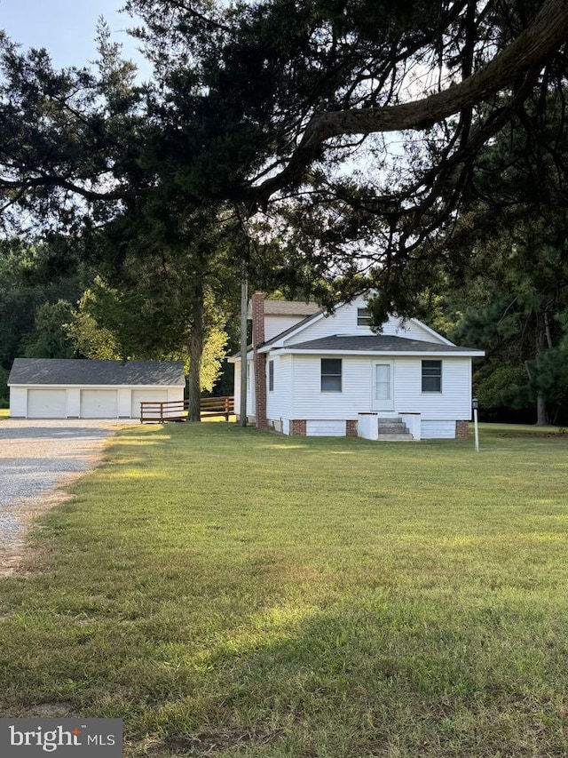 view of front of home with an outbuilding, a front yard, and a garage