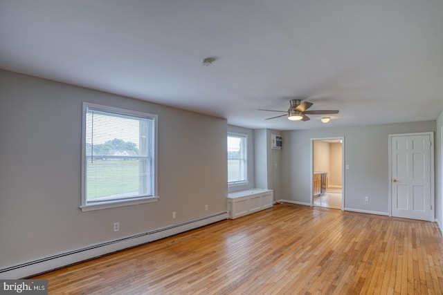 spare room featuring a baseboard radiator, a wall mounted AC, ceiling fan, and light hardwood / wood-style floors