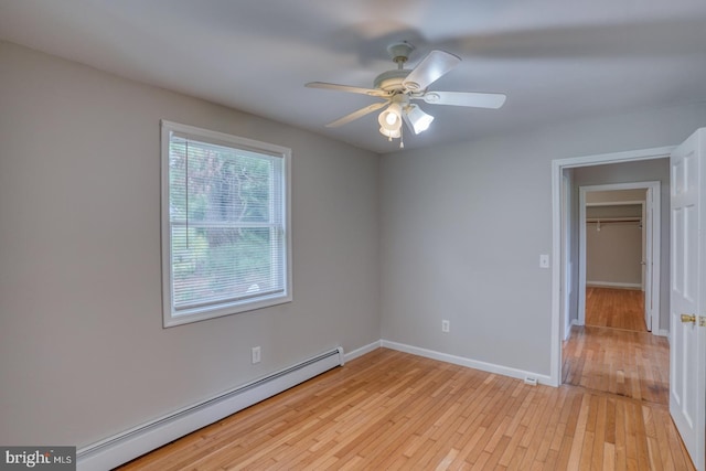 unfurnished room with light wood-type flooring, ceiling fan, and baseboard heating