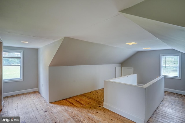 bonus room featuring lofted ceiling, a healthy amount of sunlight, and light hardwood / wood-style flooring