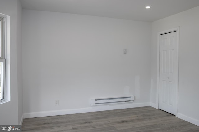 unfurnished room featuring baseboard heating and light hardwood / wood-style floors