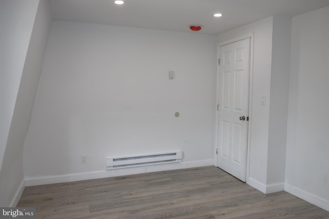 empty room with light wood-type flooring and a baseboard heating unit