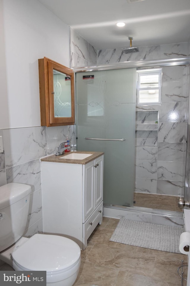 bathroom with vanity, toilet, an enclosed shower, and tile walls