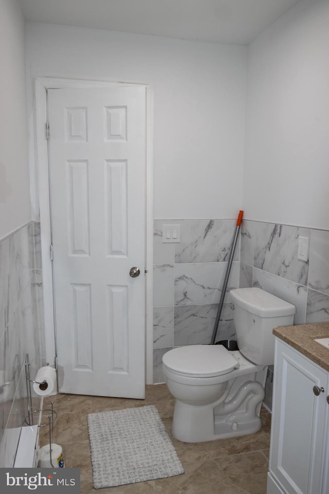 bathroom with tile patterned floors, vanity, toilet, and tile walls