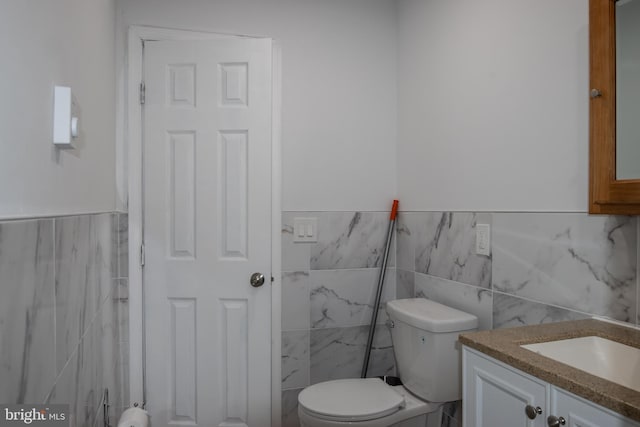 bathroom featuring vanity, tile walls, and toilet