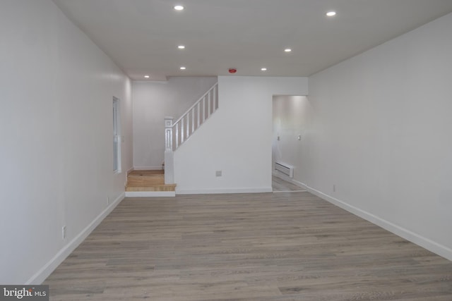 unfurnished living room featuring a baseboard radiator and light hardwood / wood-style flooring