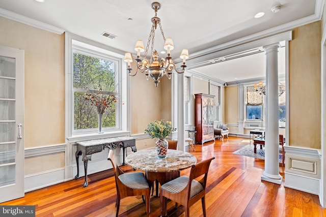 dining area featuring plenty of natural light, an inviting chandelier, crown molding, and decorative columns