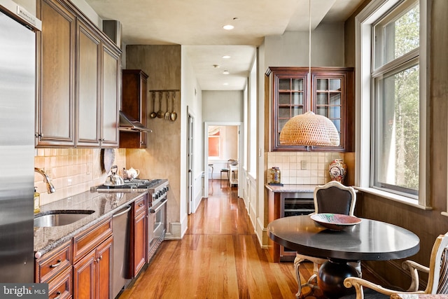 kitchen with backsplash, stone counters, sink, and appliances with stainless steel finishes