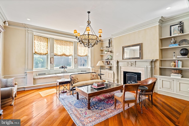 living area with built in shelves, light hardwood / wood-style floors, crown molding, and a chandelier