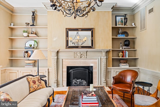 living area with hardwood / wood-style flooring, built in shelves, ornamental molding, and a fireplace