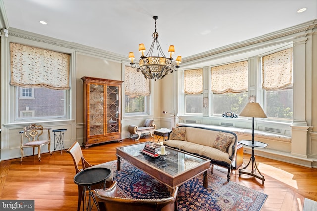 interior space with light hardwood / wood-style floors, ornamental molding, and an inviting chandelier