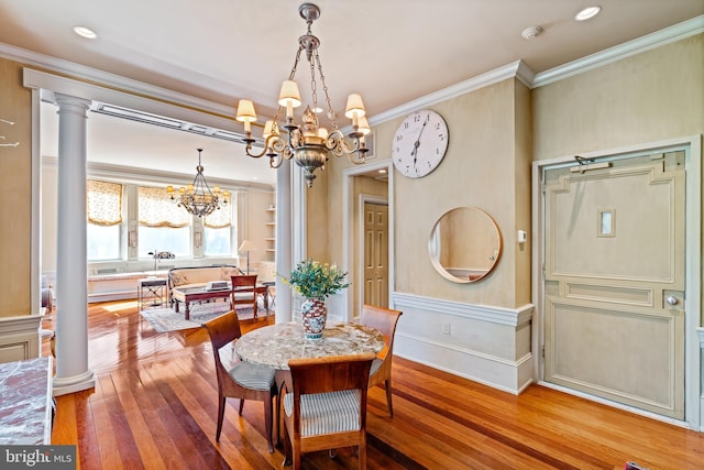 dining area featuring a chandelier, hardwood / wood-style floors, decorative columns, and crown molding