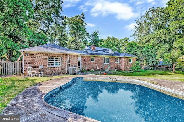 view of pool with a lawn and central air condition unit