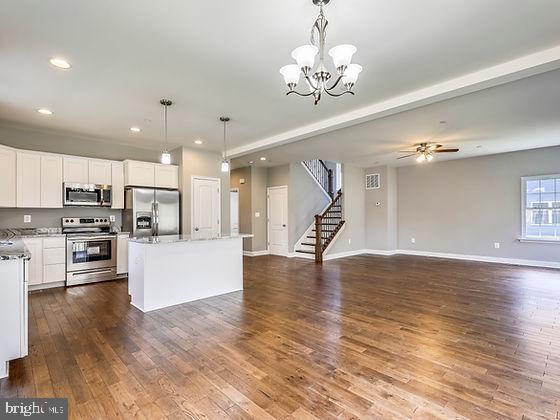 kitchen with a kitchen island, dark wood-type flooring, decorative light fixtures, and appliances with stainless steel finishes