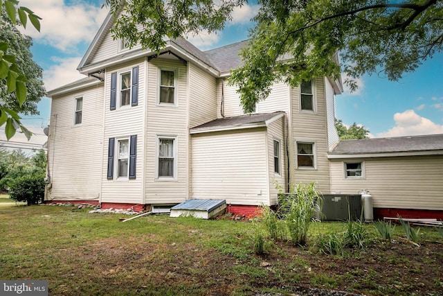 back of house featuring a lawn and central air condition unit