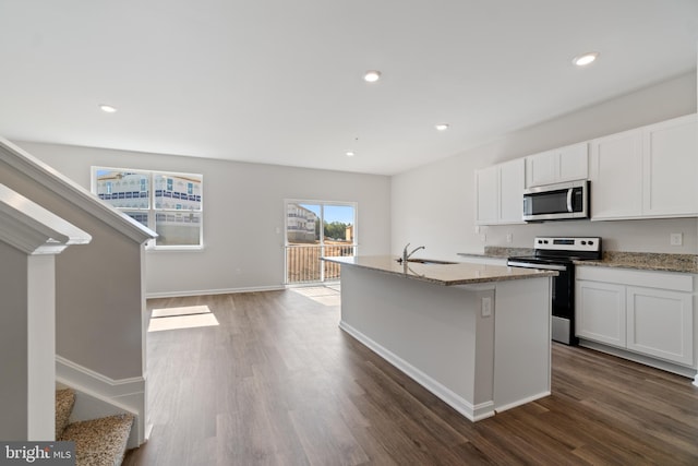 kitchen featuring dark hardwood / wood-style flooring, stainless steel appliances, sink, white cabinetry, and an island with sink