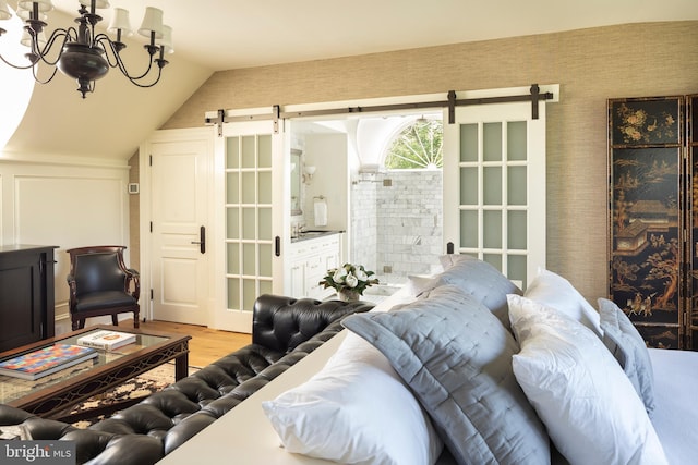 living room with a barn door, light hardwood / wood-style floors, vaulted ceiling, and a notable chandelier