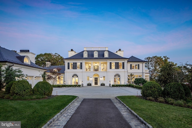 view of front of house featuring a balcony and a lawn