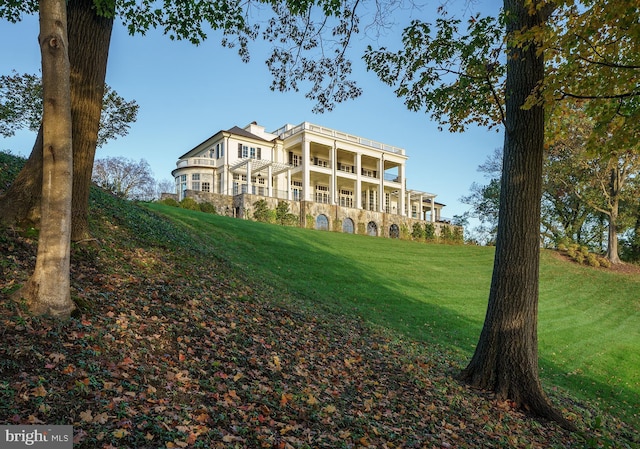 rear view of property featuring a yard and a balcony