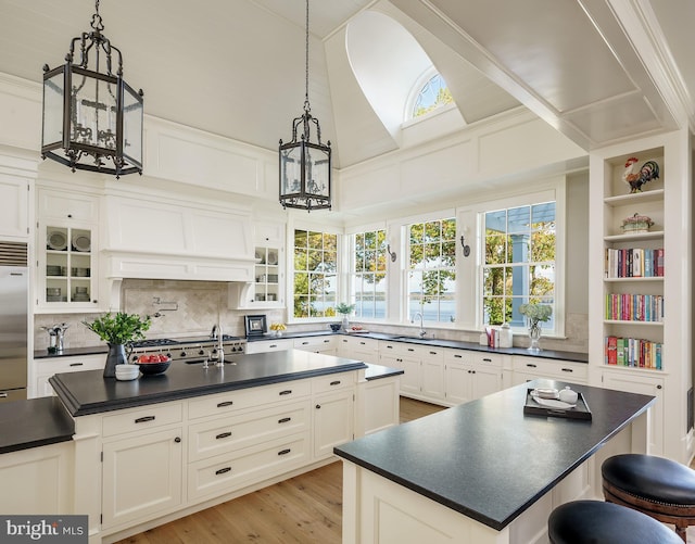 kitchen with pendant lighting, a center island with sink, a skylight, and built in fridge