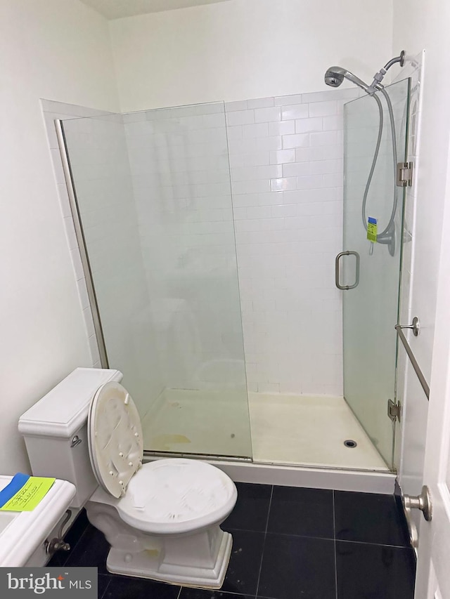 bathroom featuring tile patterned floors, toilet, and a shower with shower door