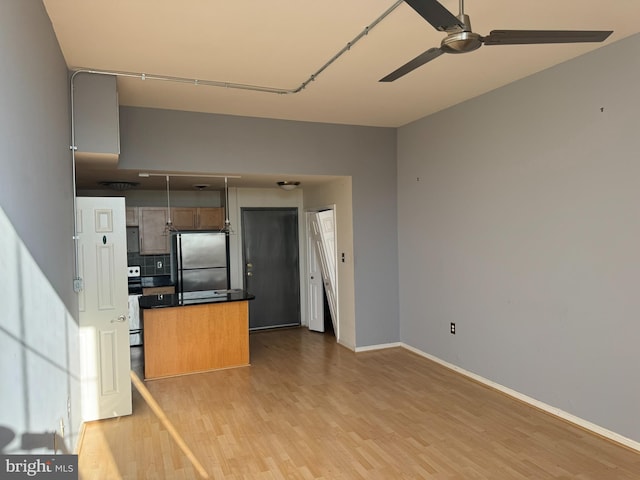 kitchen with tasteful backsplash, a kitchen island, ceiling fan, light hardwood / wood-style floors, and stainless steel refrigerator