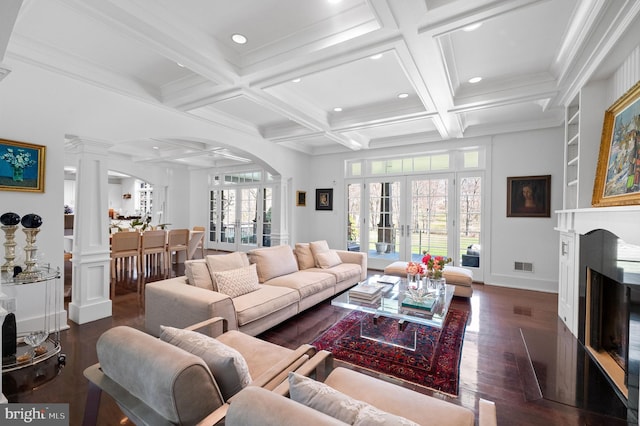 living room with beam ceiling, dark hardwood / wood-style flooring, french doors, and decorative columns