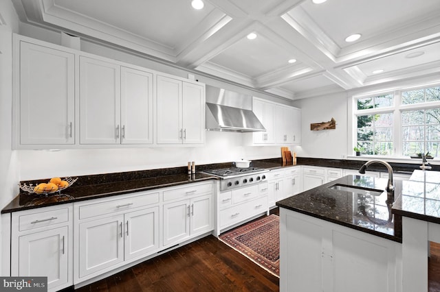 kitchen featuring wall chimney range hood, white cabinets, stainless steel gas stovetop, and sink