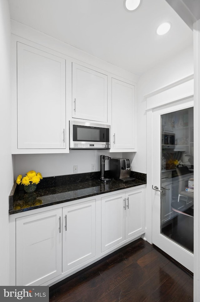 kitchen featuring dark hardwood / wood-style flooring, white cabinetry, and dark stone countertops