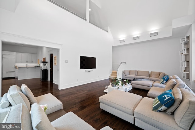 living room featuring a high ceiling and dark wood-type flooring