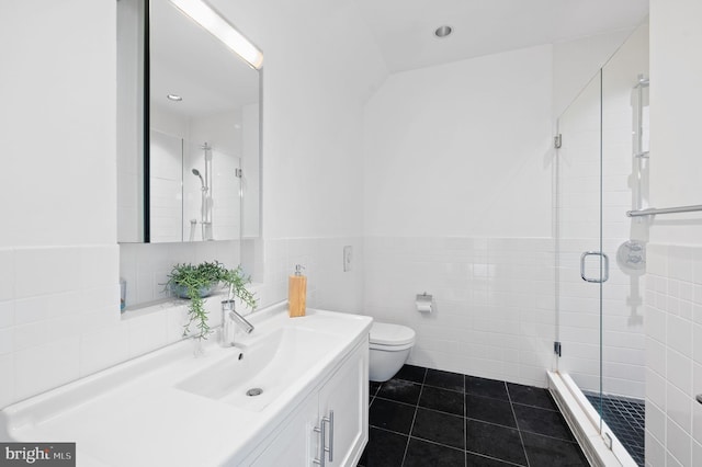 bathroom featuring tile patterned flooring, toilet, a shower with door, vanity, and tile walls