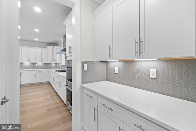 kitchen with white cabinets, light stone counters, backsplash, and stainless steel appliances