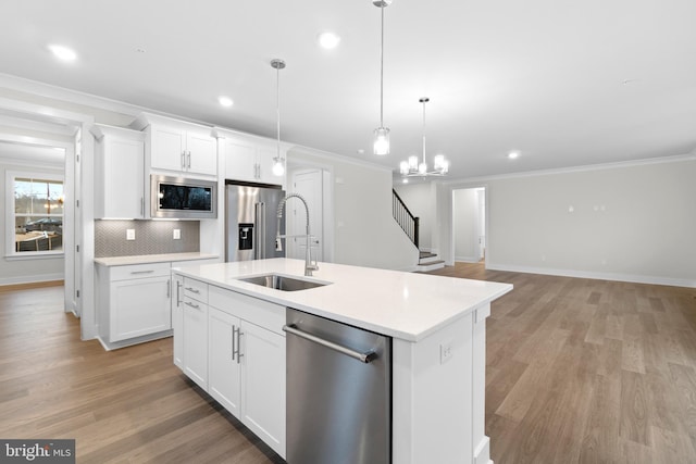 kitchen featuring pendant lighting, white cabinets, sink, an island with sink, and stainless steel appliances