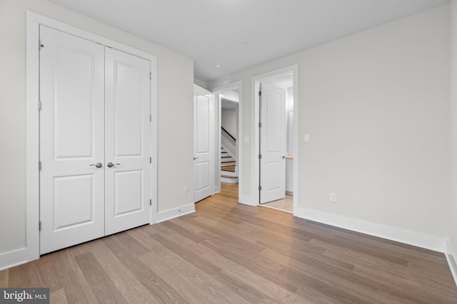 unfurnished bedroom with light hardwood / wood-style flooring and a closet