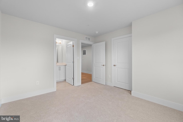 unfurnished bedroom with light colored carpet and ensuite bath