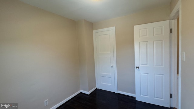 unfurnished bedroom with dark wood-type flooring