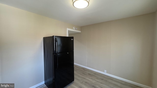 kitchen with light hardwood / wood-style floors and black refrigerator