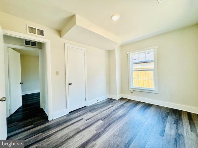 unfurnished bedroom with a closet and dark hardwood / wood-style floors