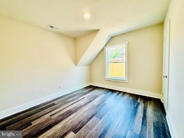 additional living space with vaulted ceiling and dark wood-type flooring