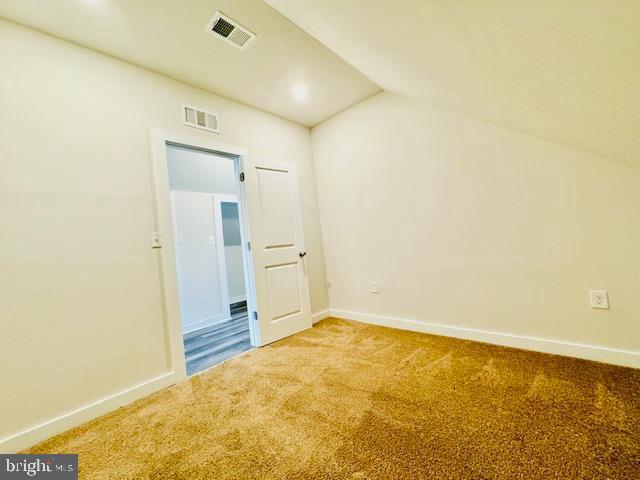 spare room featuring lofted ceiling and carpet floors