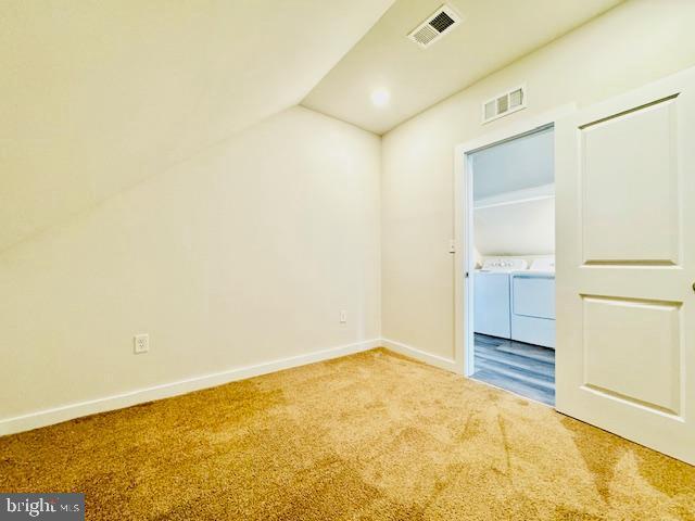 empty room with carpet floors, vaulted ceiling, and independent washer and dryer