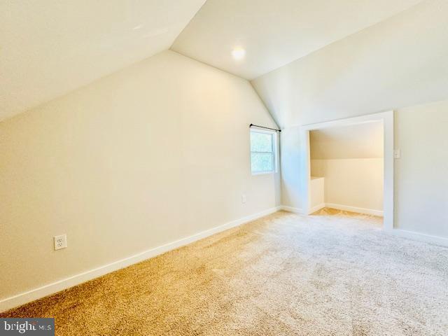 additional living space with carpet flooring and lofted ceiling