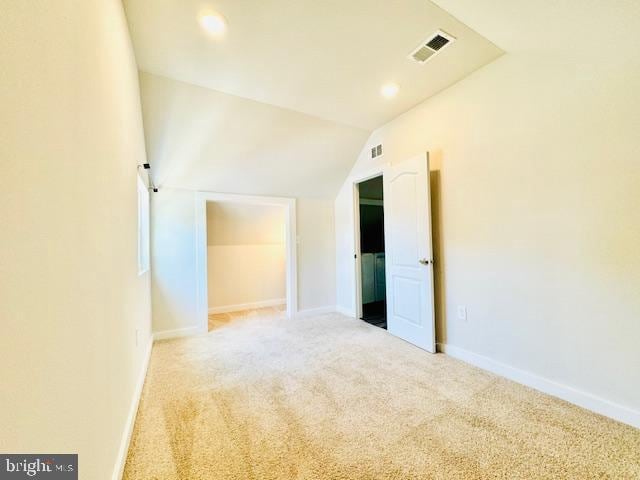 carpeted spare room featuring vaulted ceiling