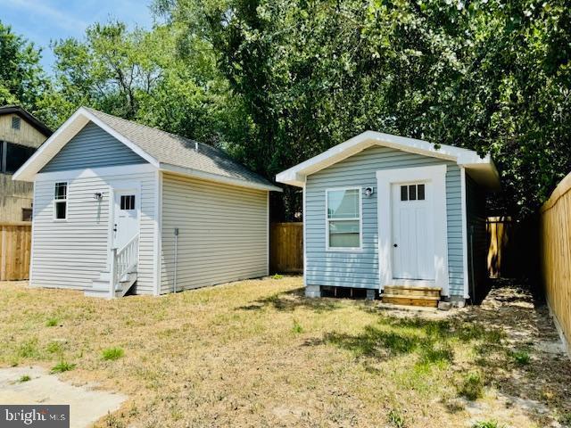 back of property with a shed and a lawn