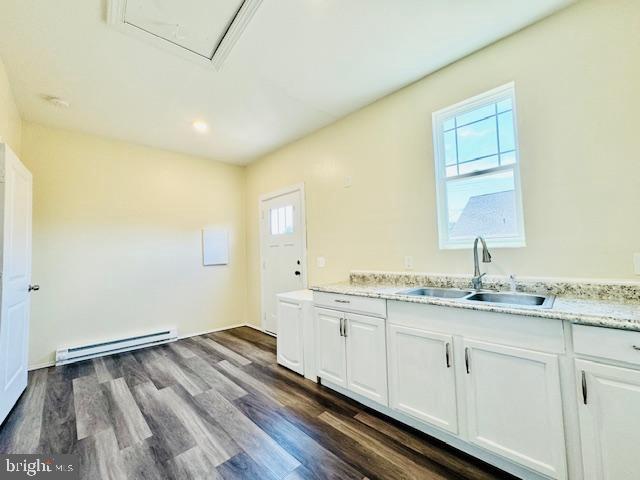 kitchen with dark wood-type flooring, white cabinetry, a baseboard heating unit, and sink