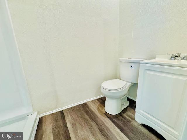 bathroom featuring toilet, vanity, and hardwood / wood-style flooring