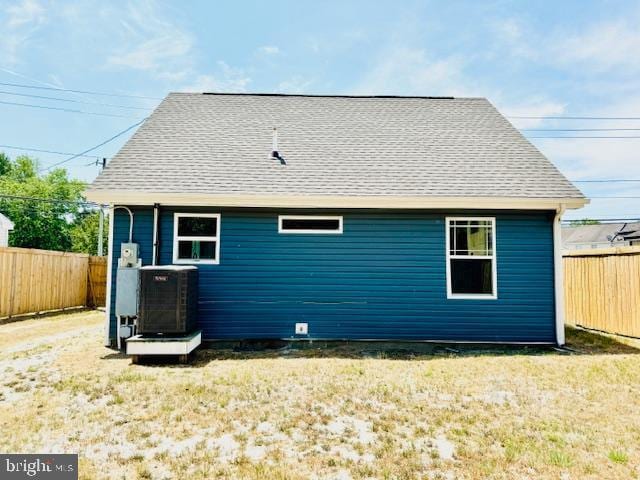 back of property with central AC and a lawn