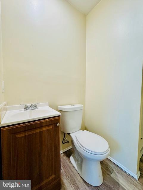 bathroom featuring wood-type flooring, vanity, and toilet