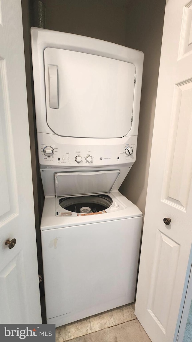 clothes washing area featuring light tile patterned floors and stacked washer / dryer